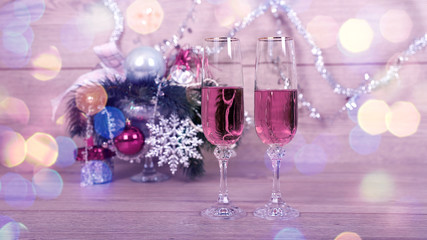 Новогодняя открытка, два фужера с розовым шампанским на фоне елки, игрушек, гирлянды - obrazy, fototapety, plakaty