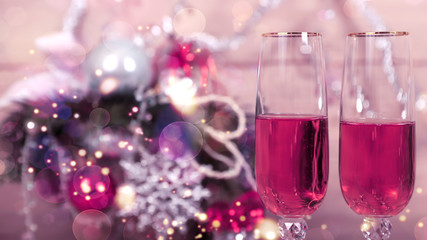 Новогодняя открытка, два фужера с розовым шампанским на фоне елки, игрушек, гирлянды