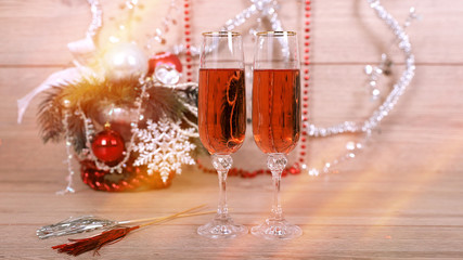 Новогодняя открытка, два фужера с розовым шампанским на фоне елки, игрушек, гирлянды - obrazy, fototapety, plakaty