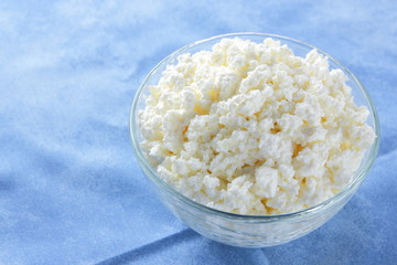 Cottage cheese. Cottage cheese on blue napkin. Soft cheese in glassware. Dairy product for breakfast. Copy space