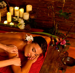 Obraz na płótnie Canvas Aromatherapy massage of woman in spa salon. Girl on candles background treats problem health . Luxary interior with working masseuse. Indian back Massage as pain relief for female