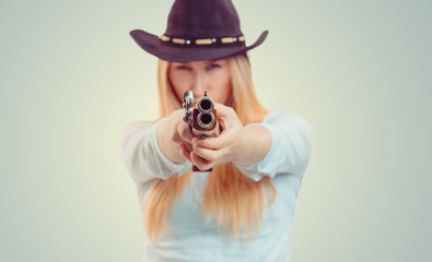 Cowgirl aiming at camera with gun