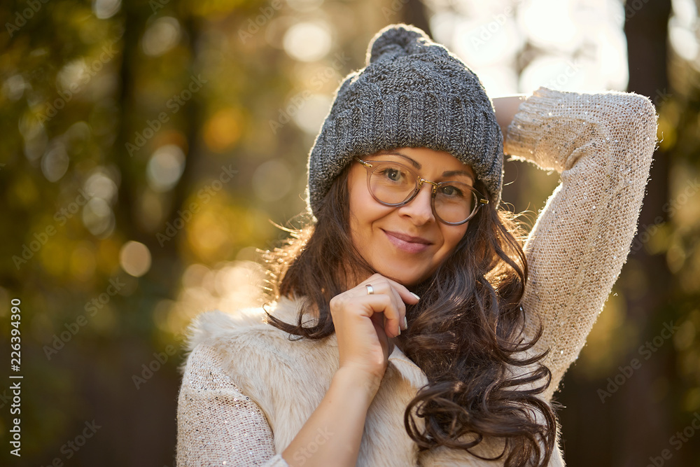 Wall mural face of a beautiful woman in a cap and glasses on a background of autumn forest