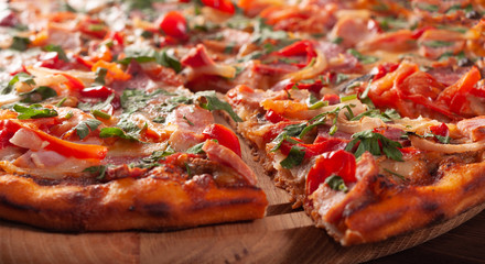 Appetizing pizza with a cut off piece on a chopping board, close-up