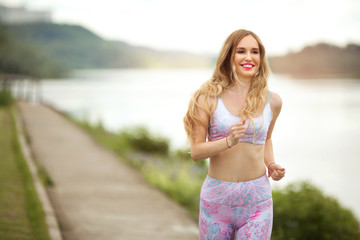 beautiful young girl with flowing hair runs on nature in the summer in a tracksuit