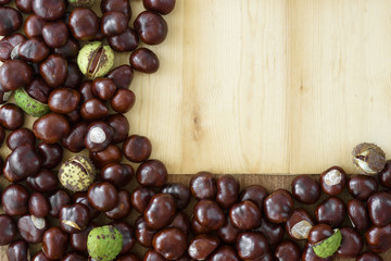 Obraz premium Top view of scattered chestnuts created in a frame and copy space on wooden background.