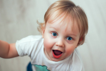 Naklejka premium Portrait of a one year old beautiful surprised little boy with blue eyes and blond hair
