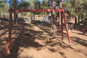 Fototapeta na wymiar Red swing in a recreational area in the bush