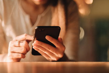 Hand of woman using smartphone on wooden table,Space for text or design.