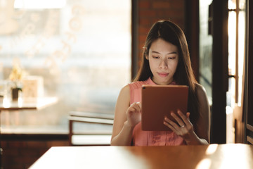 Woman looking on her tablet for social network in coffee cafe.