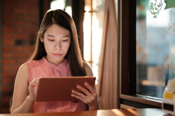 Woman looking on her tablet for social network in coffee cafe.