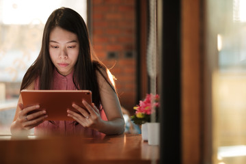 Woman looking on her tablet for social network in coffee cafe.