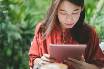 Woman holding tablet computer and coffee cup in coffee shop.
