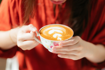 Hand of woman holding a cup of latte art coffee.