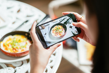 Woman hands take photography of food with smart phone in restaurant,Smartphone photo for social network post.