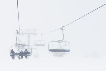 The chair alpine skiing lift in fog. cloudy snow day in mountains.