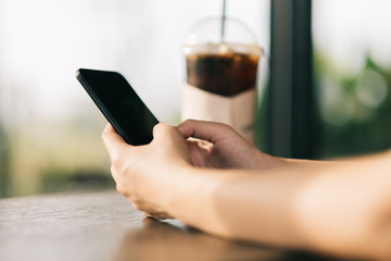 Hand of woman using smart phone in coffee shop.