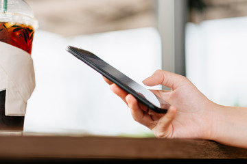 Hand of woman using smart phone in coffee shop.
