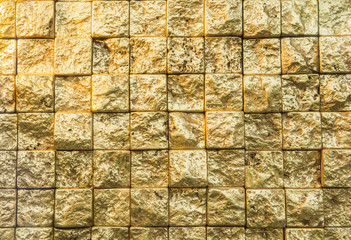 Bumpy golden small even squares brick wall background.