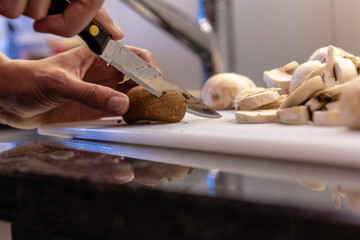 anschneiden eines braunen pilzes mit dem messer auf dem schneidebrett