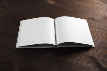 Open book or notebook with blank pages on wood table background.