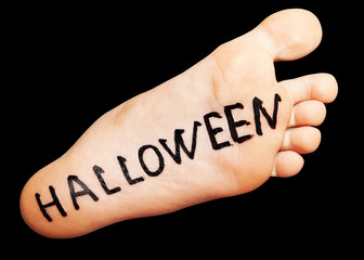 Halloween inscription in black on the foot, isolated on a black background.