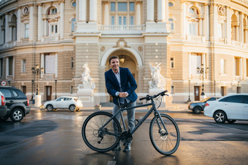 Portrait of handsome young man with his bicycle on the street in city center during sunrise