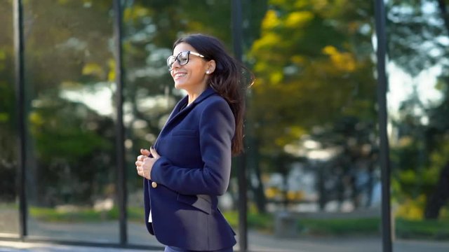 Beautiful businesswoman coming out from office building in excellent mood, she successfully presented the project, won. Success, achievement in business, young specialist concept