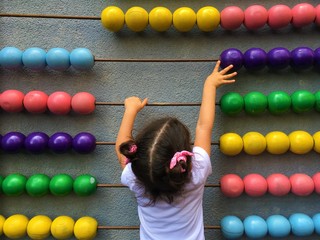 A cute girl playing with wooden abacus. Educational concept for kids. Learing to count. Math for...