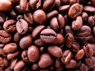 Naklejka premium Macro close up of dense bunch of aromatic roasted brown coffee beans shot in soft daylight