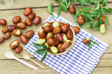 Obraz premium Wicker basket with fruits Ziziphus real, capiente, jujube, Chinese date, capiinit, jojoba, Chinese-date (lat.Ziziphus jujuba) and wooden spoons on a napkin