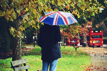 Man holding an umbrella in a rainy day. Rainy weather in London. England flag umbrella 