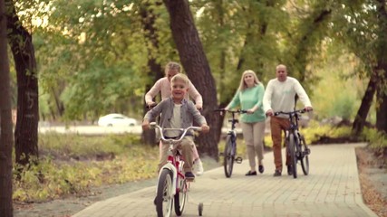 Authentic happy family resting in a Park with a baby boy on the bike. early autumn in the Park lifestyle. Family holidays on bikes