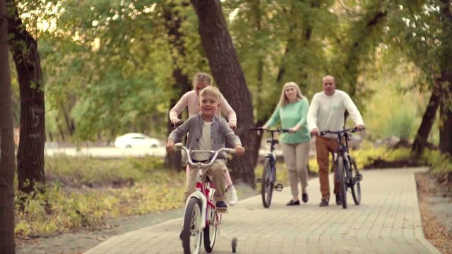 Authentic happy family resting in a Park with a baby boy on the bike. early autumn in the Park lifestyle. Family holidays on bikes