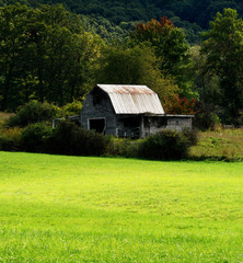 Fototapeta premium An old rustic barn across a green meadow in rural West Virginia.