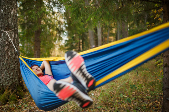 Image of happy brunette lying in hammock in woods
