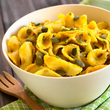 Pasta with pumpkin and parsley sauce, sprinkled with pumpkin seeds and served in a bowl, photographed with natural light (Selective Focus, Focus in the middle of the dish)