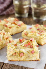 Fresh homemade traditional German Zwiebelkuchen onion cake savory baked pastry or pie made of yeast dough topped with onion, bacon, eggs, cream (Selective Focus in the middle of the first cake piece)