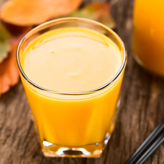 Fresh homemade pumpkin smoothie in glass with drinking straws on the side, photographed on wood (Selective Focus, Focus on the front rim of the glass)