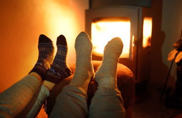 Couple wearing woollen socks near fireplace