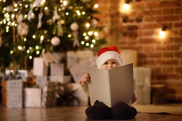 Little boy reading a magic book in decorated cozy living room