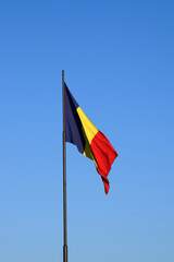 Romanian flag waving in the wind in front of a clean blue sky. Romania National Flag.