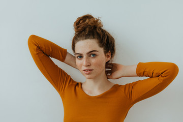 Woman portrait. Style. Beautiful blue eyed girl with freckles is raising her hands while posing at...