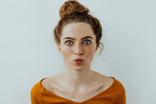 Woman Portrait. Style. Beautiful Blue Eyed Girl With Freckles Is Pouting Lips At Camera, On A White Background