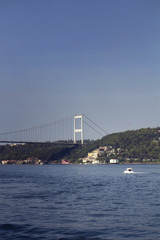 View of a white luxury yacht, FSM bridge, Bosphorus and Asian side of Istanbul. It is a sunny summer day.