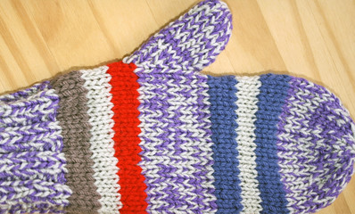 Bright and colorful handmade knitted mitten in red, purple, blue and white stripes 
