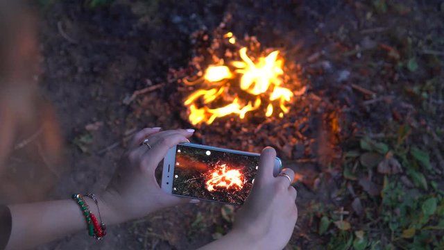 The woman shot bright bonfire with the smartphone (camping video)