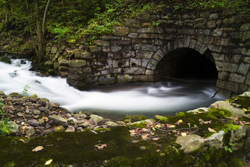 Fototapeta na wymiar Stream Flowing Into Old Stone Tunnel 