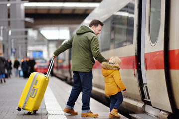 Little boy and his father go in express train on railway station platform