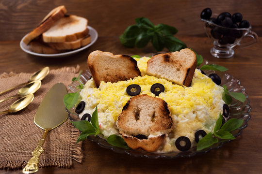 Egg salad with cheese and crab meat, toasted toast, basil  leaves, pickled olives, the image of the pig's head – the symbol of 2019.